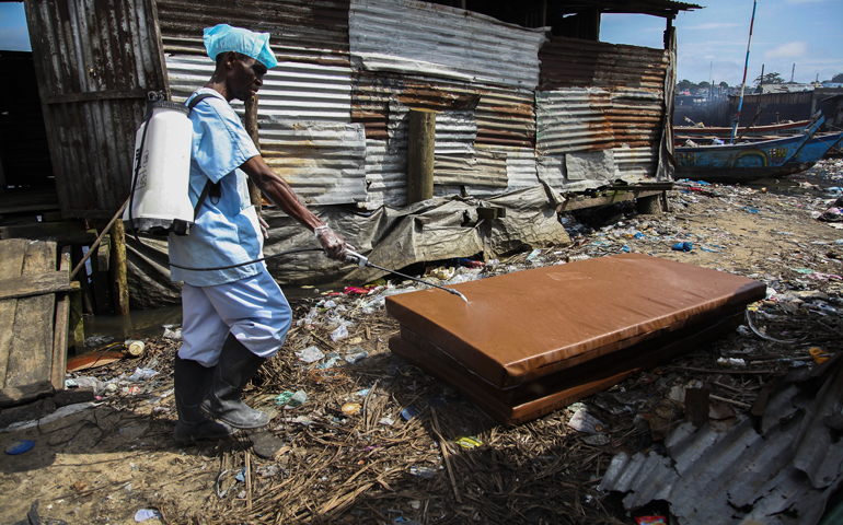 A Liberian nurse disinfects a looted mattress taken from a school that was used as an Ebola isolation unit in Monrovia, Liberia, on Tuesday. (CNS/EPA/Ahmed Jallanzo)