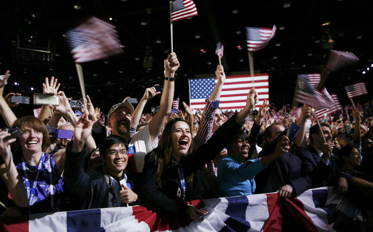People wave flags as they listen to President Barack Obama give his victory speech Wednesday in Chicago. (CNS/Reuters/Kevin Lamarque)