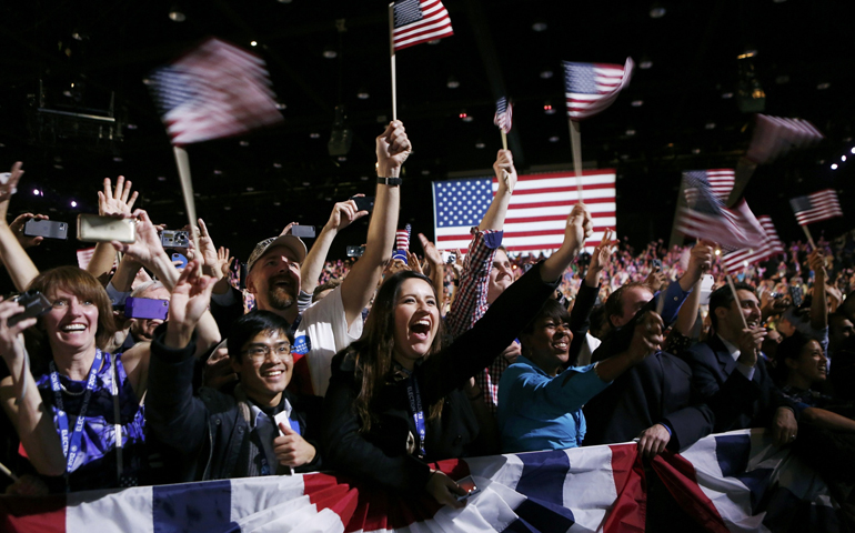 People wave flags as they listen to President Barack Obama give his victory speech Wednesday in Chicago. (CNS/Reuters/Kevin Lamarque)