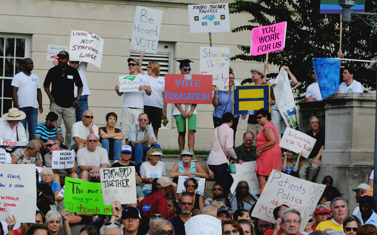 Protesters hold up signs at a Moral Monday rally Sept. 15 in Wilmington, N.C. (AP/The Star-News/Mike Spencer)
