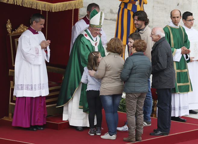 Pope Francis greets a family as they present the offertory gifts during a Mass for families Oct. 27 in St. Peter's Square at the Vatican. The Mass was the culmination of the Year of Faith pilgrimage of families. (CNS/Paul Haring) 