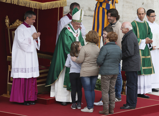 Pope Francis greets a family as they present the offertory gifts during a Mass for families Oct. 27 in St. Peter's Square at the Vatican. The Mass was the culmination of the Year of Faith pilgrimage of families. (CNS/Paul Haring)