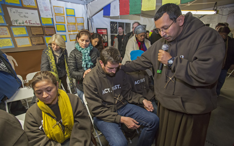Franciscan Br. Juan Turios of Action Network prays Nov. 30 with immigration reform advocates taking part in Fast for Families in a tent on the National Mall near the U.S. Capitol in Washington. (CNS/Jim West) 