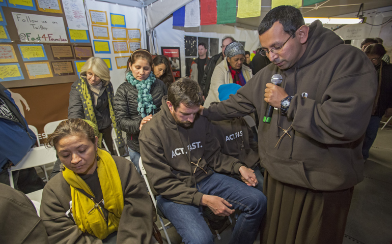 Franciscan Br. Juan Turios of Action Network prays Nov. 30 with immigration reform advocates taking part in Fast for Families in a tent on the National Mall near the U.S. Capitol in Washington. (CNS/Jim West)