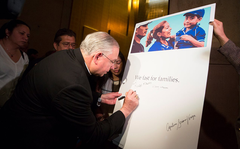 Los Angeles Archbishop Jose Gomez signs a board Tuesday supporting Fast for Families in their fast for immigration reform in front of the U.S. Capitol and at locations across the country. (Courtesy of the archdiocese of Los Angeles)