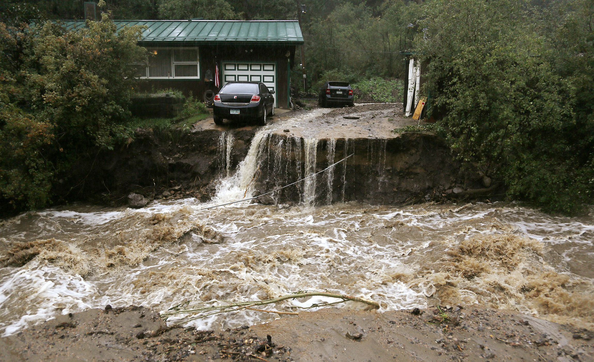 A home and car are seen Thursday after a flash flood in Coal Creek destroyed a bridge near Golden, Colo. (CNS/Reuters/Rick Wilking)