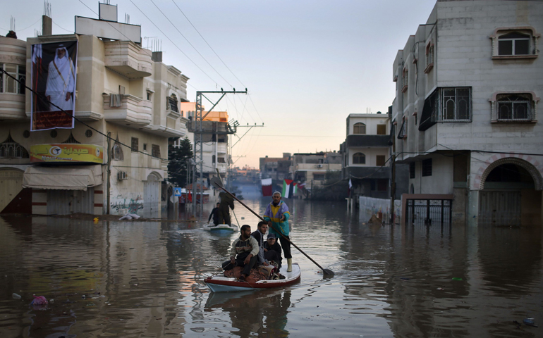 Palestinian civil defense volunteers paddle a boat to evacuate people Dec.16 from their flooded houses in the northern Gaza Strip. (CNS/Reuters/Mohammed Salem)