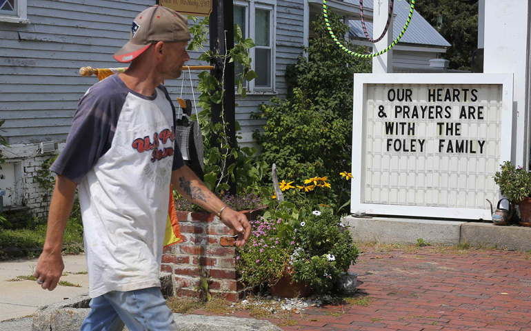 A man walks past a sign outside a shop Aug. 20 put up in memory of James Foley in his hometown of Rochester, N.H. (CNS/Reuters/Brian Snyder)