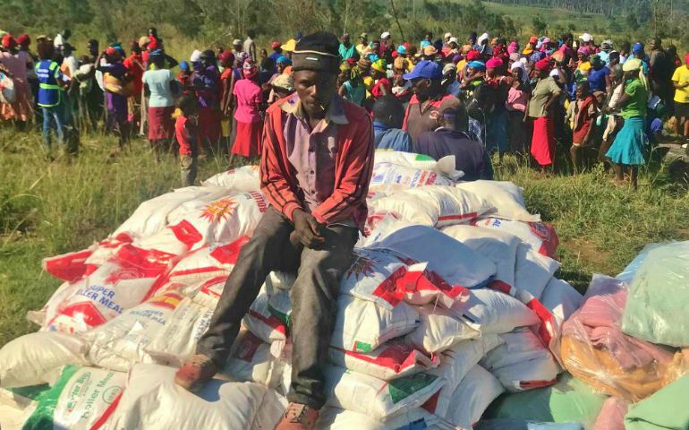An unidentified man sits on bags of corn meal as other victims were registering their names to receive aid from the nuns in Zimbabwe. (Frank Chikowore) 
