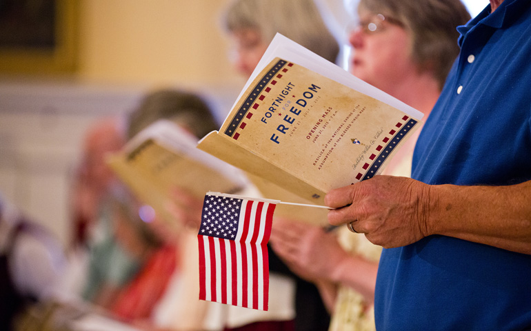 A man holds a program and U.S. flag during the opening Mass for the second annual Fortnight for Freedom observance Friday at the Basilica of the National Shrine of the Assumption of the Blessed Virgin Mary in Baltimore. (CNS/Catholic Review/Tom McCarthy Jr.)