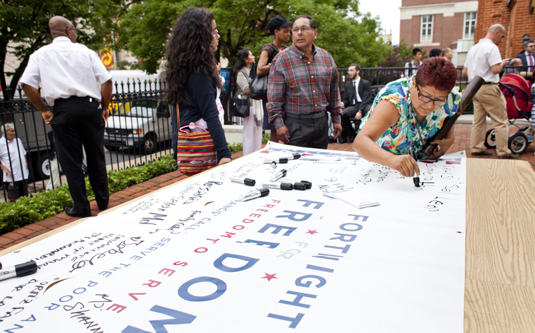 Simeona Leon, a member of the Neocatechumenal Way, signs the Fortnight for Freedom banner Saturday outside the Basilica of the National Shrine of the Assumption of the Blessed Virgin Mary in Baltimore. (CNS/Catholic Review/Tom McCarthy Jr.)