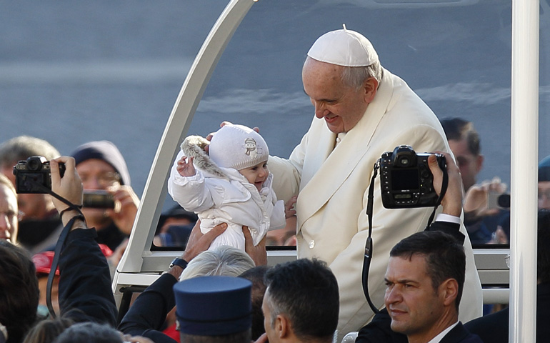 Pope Francis greets a baby during his general audience Wednesday in St. Peter's Square at the Vatican. (CNS/Paul Haring) 
