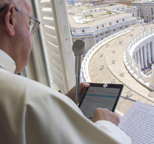 Pope Francis uses a tablet Sunday, officially opening online registration for World Youth Day 2016 in Poland from the window of his studio overlooking St. Peter's Square at the Vatican. (CNS/EPA/L'Osservatore Romano)