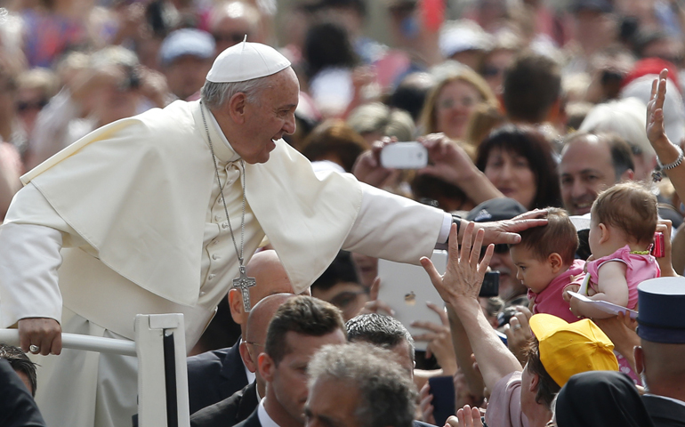 Pope Francis greets a baby as he arrives to lead his general audience Wednesday in St. Peter's Square at the Vatican. (CNS/Paul Haring)