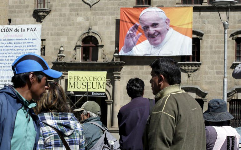 People walk past an image of Pope Francis in La Paz, Bolivia, June 30. (CNS/Reuters/David Mercado)
