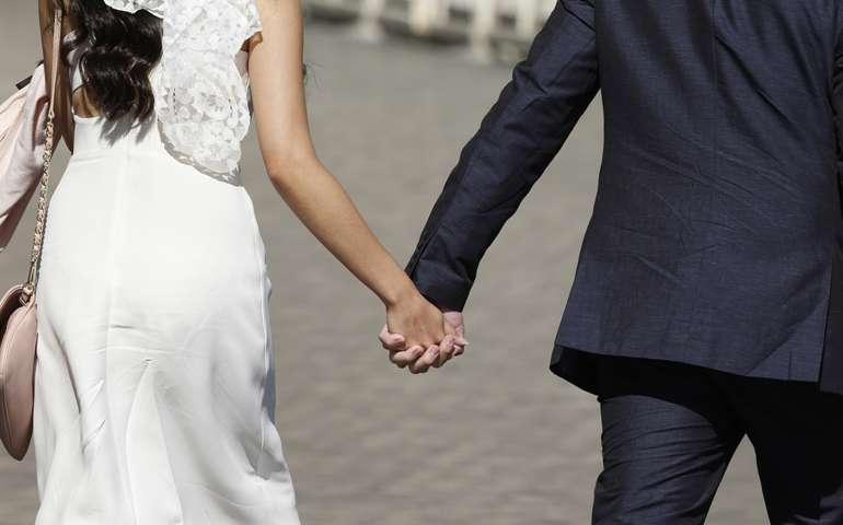 A newly married couple hold hands as they arrive for Pope Francis' general audience Wednesday in St. Peter's Square at the Vatican. (CNS/Paul Haring)