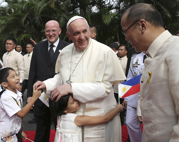 President Benigno Aquino III of the Philippines looks on as a girl embraces Pope Francis after a Jan. 16 welcoming ceremony at the Malacanang Palace in Manila. (CNS/Reuters/Ryeshen Egagamao)