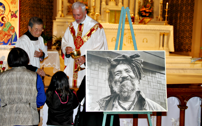 Mourners receive Communion from Fr. Joseph Illo, pastor of Star of the Sea Church in San Francisco, during a Nov. 7 funeral Mass for Thomas Myron Hooker, a homeless man pictured in a portrait near the altar. (CNS/Catholic San Francisco/Christina Gray)