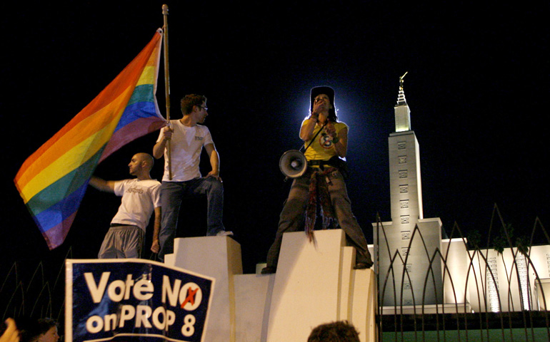Robert Oliver holds a rainbow colored flag as a woman talks to a crowd outside the Los Angeles California Temple of the Church of Jesus Christ of Latter-day Saints during a "No on Prop 8" march and rally in 2008, two days after Californians approved Proposition 8. The measure defines marriage as the union between one man and one woman.(CNS/Reuters/Danny Moloshok)