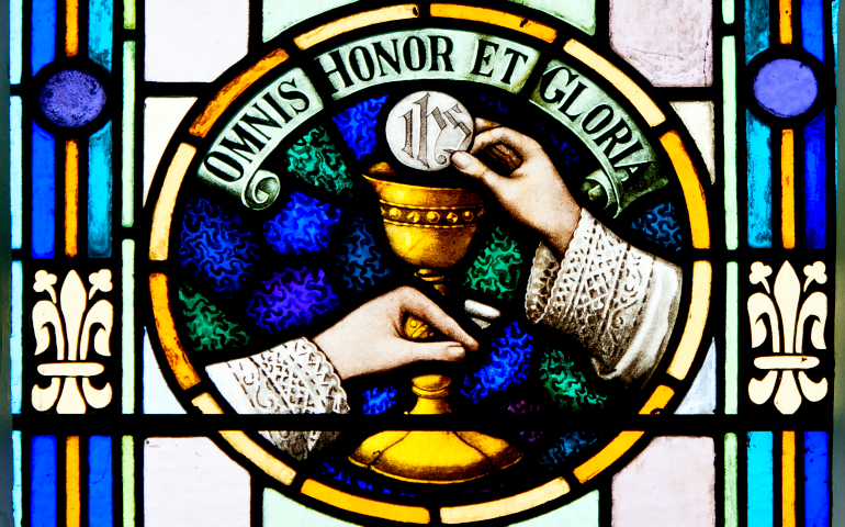 A stained glass window in a church in County Kerry, Ireland, shows a priest's hands during the Eucharistic Prayer. Irish priests' ever-increasing workload is threatening to turn this demoralized and declining group into "sacrament-dispensing machines," says Fr. Brendan Hoban. (Wikimedia Commons/Andreas F. Borchert)