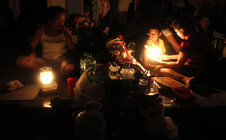 Homeless survivors of Typhoon Haiyan rest Wednesday under candlelight inside a Catholic church in Tacloban, Philippines. (CNS/Reuters/Romeo Ranoco)