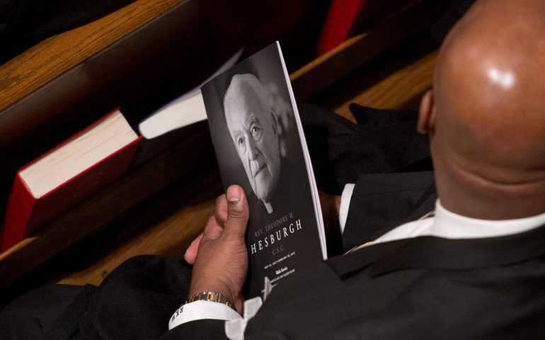 A man holds a program with an image of Holy Cross Fr. Theodore Hesburgh at a visitation and wake for the late priest Tuesday at the Basilica of the Sacred Heart on the campus of the University of Notre Dame in Indiana. (CNS/University of Notre Dame/Matt Cashore)