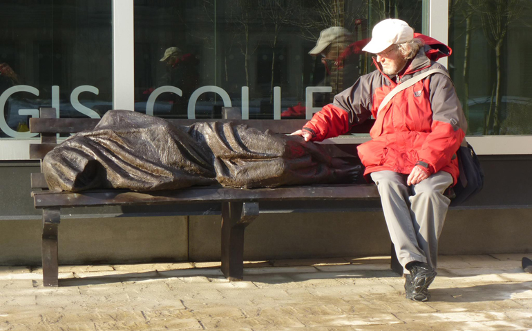 Peter Larisey sits alongside the "Homeless Jesus" sculpture. (RNS/Courtesy of Timothy Schmalz)
