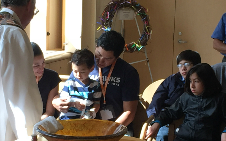 Deacon Denny Duffell baptizes Tiago in April 2016 during a Mass held at Seattle Children's interfaith chapel, with parents Geomara and Conan Viernes, sister Carissa Martinez, and aunt and godmother Yesenia Cardenas looking on. (Hector Cardenas)