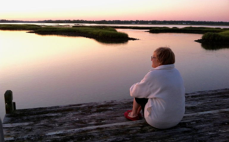 A visitor watches the sunset from the dock overlooking the expansive wetlands near Innisfree House.