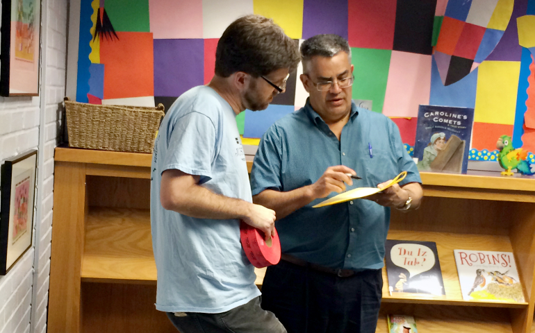 Simon Sandoval-Moshenberg, left, attorney for Legal Aid Justice Center, chats with Frank Nieves, an attorney volunteering at the immigration consultation clinic, about a case. (Julie Bourbon)