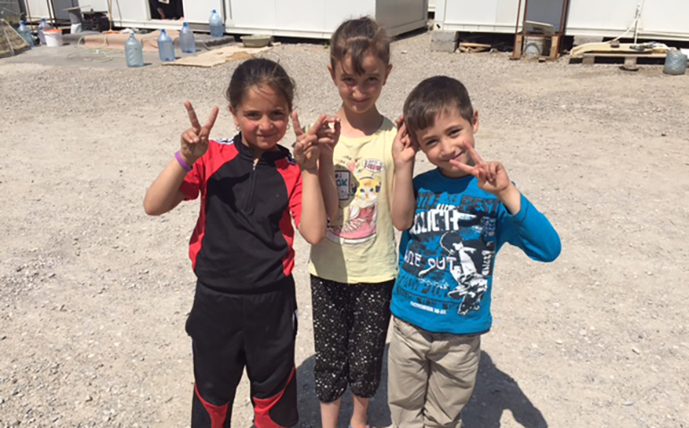 Three Iraqi kids flashing the peace sign at a displacement camp in Ankawa, Iraq. (NCR/Tom Gallagher)