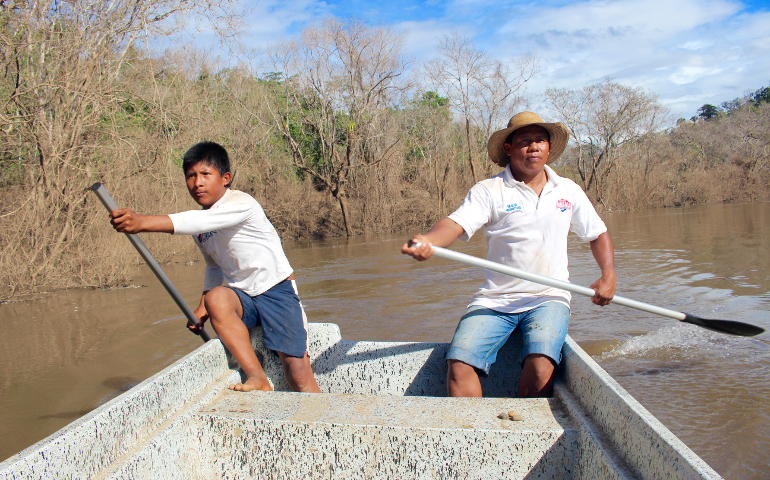 Döegeo Gallardo and Göejet Miranda paddle home through the dead zone that was once a shady, fish-filled river. (Tracy L. Barnett)