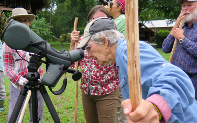 Maryknoll Sr. Melinda Roper looks through a telescope to see a three-toed sloth in a cuipo tree at the Maryknoll sisters' pastoral center. (Tracy L. Barnett) 