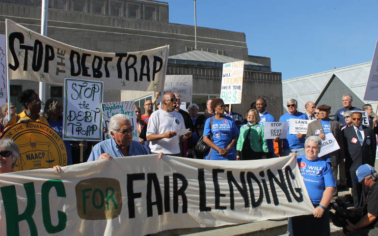 Elliott Clark, center, tells his story of payday loans that grew to $50,000 to a crowd at Barney Allis Plaza, in downtown Kansas City, Mo., before a federal hearing on predatory loans June 2, 2016. (NCR photos/Brian Roewe)