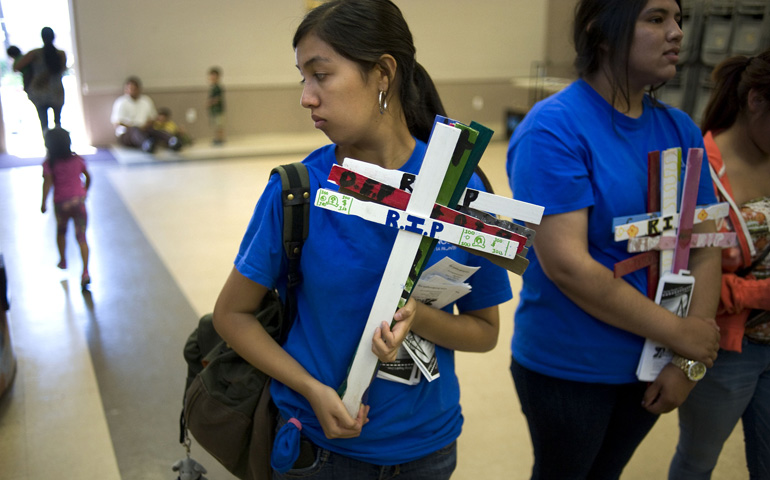 Activists with the immigration rights group Border Angels carry wooden crosses to a U.S. bishops' news conference on immigration reform legislation Monday at Our Lady of Guadalupe Church in San Diego. The wooden crosses represent undocumented workers who have died crossing into the United States. (CNS/David Maung)