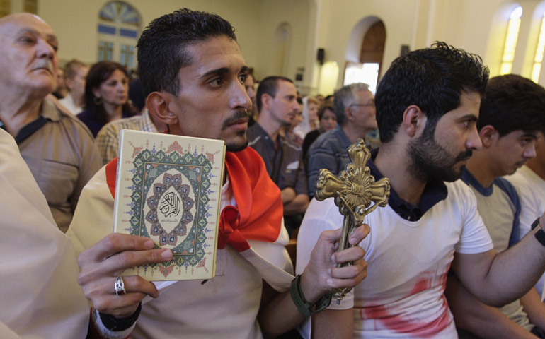 An Iraqi man carrying a cross and a Quran attends Mass Sunday at Mar Girgis Church in Baghdad. (CNS/Reuters/Ahmed Malik)