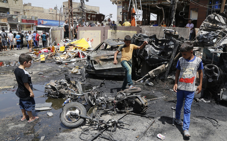 Boys look at the site of a car bomb attack on Aug. 1 in Baghdad. (CNS/Reuters/Wissm al-Okili)