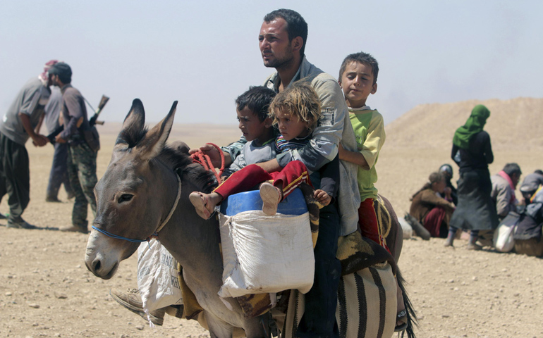 A man and three children flee violence from forces loyal to the Islamic State in Sinjar, Iraq, on Sunday. (CNS/Reuters/Rodi Said)