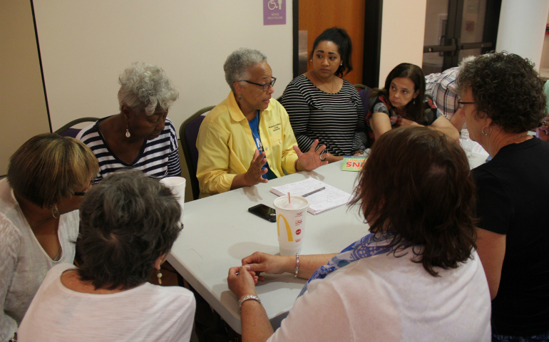 Sr. Larretta Rivera-Williams, in yellow, talks to community members of Jefferson City, Mo., at an evening caucus July 13 with Nuns on the Bus. (Courtesy of NETWORK)