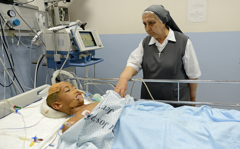 Sr. Gilbert Saliba, a member of the Sisters of St. Joseph of the Apparition, visits Nidal Alawi, 11, of Gaza in the intensive care unit of St. Joseph Hospital on Wednesday in Jerusalem. (CNS/Debbie Hill) 
