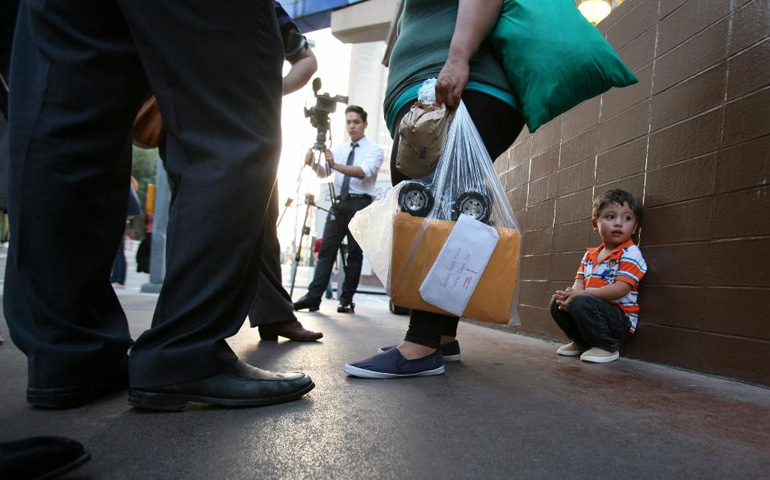 Two-year-old Alejandro Galeano finds a spot away from his mother's hand after being released from the Karnes County Residential Center in Karnes City, Texas, on April 9. His mother, Kenia Galeano, center, talks to the news media after her release. (Nuri Vallbona)