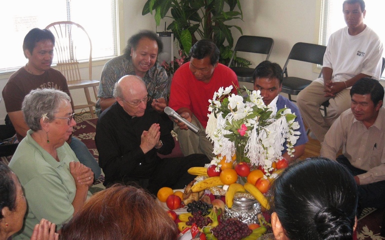 Redemptorist Fr. Don MacKinnon and Holy Family Sr. Michaela O'Connor participate in Kmhmu' community prayer around a traditional flower tree. (Courtesy of Denver Province of the Congregation of the Most Holy Redeemer)