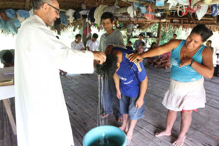 Augustinian Fr. Miguel Angel Cadenas baptizes a young man June 12 in a village along the Urituyacu River in Peru. (CNS/Barbara Fraser) 