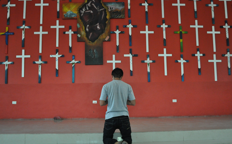 A migrant at La 72 prays in the chapel where crosses on the wall commemorate 72 migrants killed in Tamaulipas in 2010 (J. Malcolm Garcia)