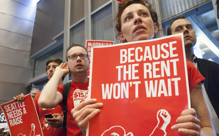 Labor activists hold signs during a Seattle City Council meeting June 2 in which the council voted on raising the minimum wage to $15 per hour. (CNS/Reuters/David Ryder)