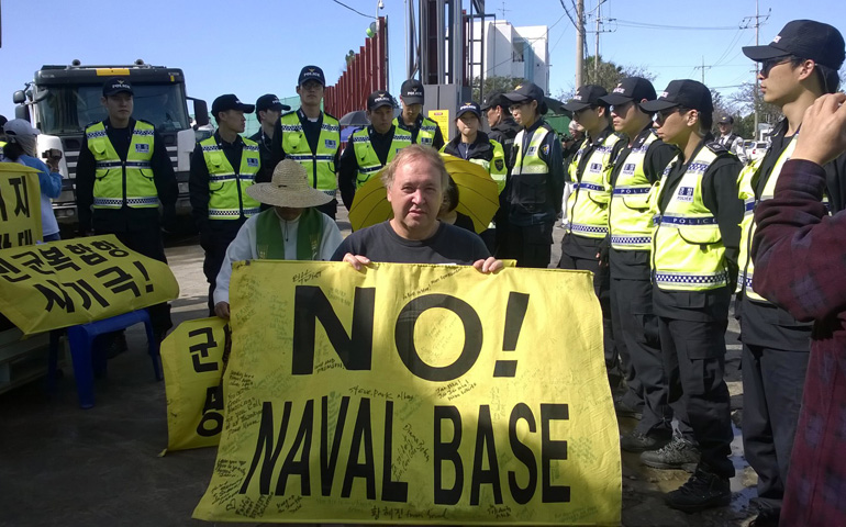 Police surround Art Laffin and other activists as they protest at the main entrance of a U.S.-backed Korean naval base on Jeju Island.