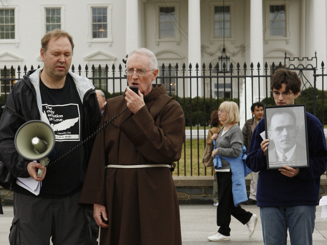 Art Laffin, holding the bullhorn on the left, stands next to Franciscan Fr. Joe Nangle during an Ash Wednesday protest against the Iraq War in front of the White House in Washington in February 2008. On the right stands the author, holding an image of Blessed Franz Jägerstätter. (CNS photo/Paul Haring)