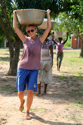 Megan Streit, a volunteer with Focus Missions, helps locals carry water to make cassava flour in Togo in June 2014. (Focus Missions)