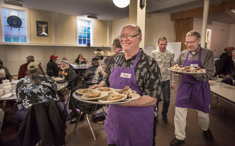 Precious Blood Frs. Jack McClure, center, and Matt Link, right, serve dessert during a Wednesday supper at Most Holy Redeemer Parish in San Francisco. (Dennis Callahan)
