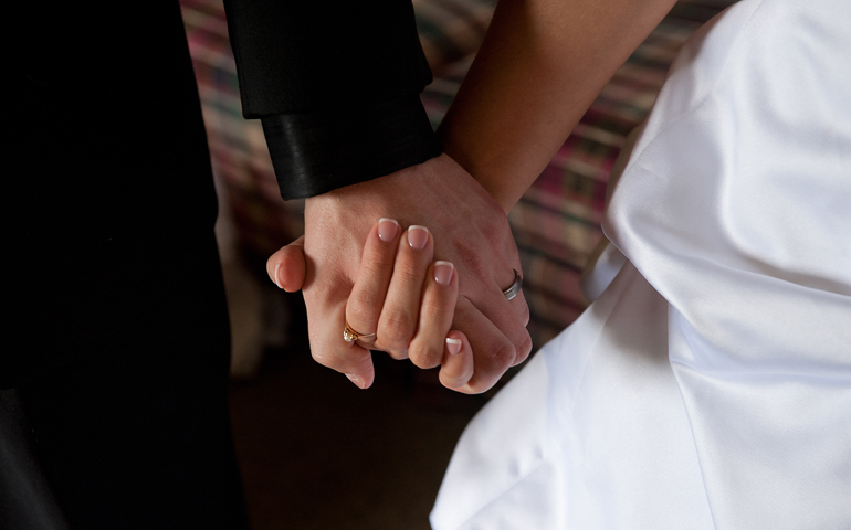 A groom and bride hold hands on their wedding day. (CNS/Jon L. Hendricks) 